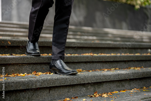 Cropped image of a businessman walking down the stairs in front of the building.