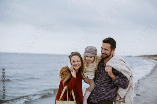 Young caucasian family spending time and walking on a beach during winter and colder weather