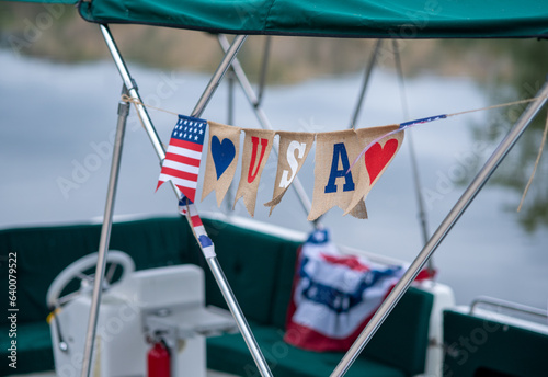 USA flag is flying on a pontoon boat on a lake