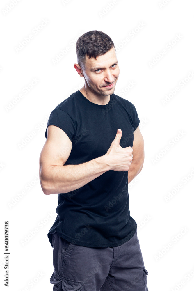 Smiling young muscular man in a black t-shirt shows like. Activity, energy and sport. Space for text. Isolated on white background. Vertical. Smiling young muscular man in a black t-shirt shows like. Activity, energy and sport. Space for text. Isolated on white background. Vertical.