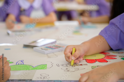 close-up photo of children Asia draws and paints watercolors or crayons on paper according to their own creativity, bright colors in the kindergarten class, the floor in the school.
