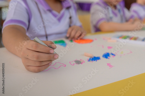 Children draw and paint water or crayons on the colorful drawing paper of their own creativity in the kindergarten class at the school.
