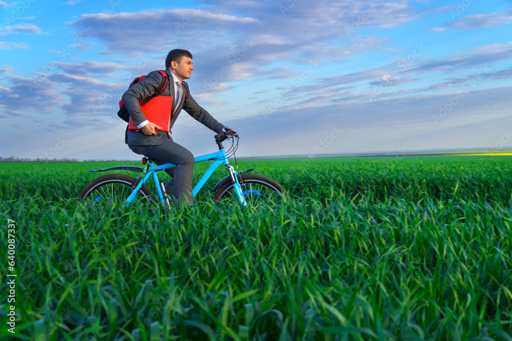 businessman rides a bicycle through a green grass field, the concept of activity, leisure or freelancing businessman rides a bicycle through a green grass field, the concept of activity, leisure or freelancing