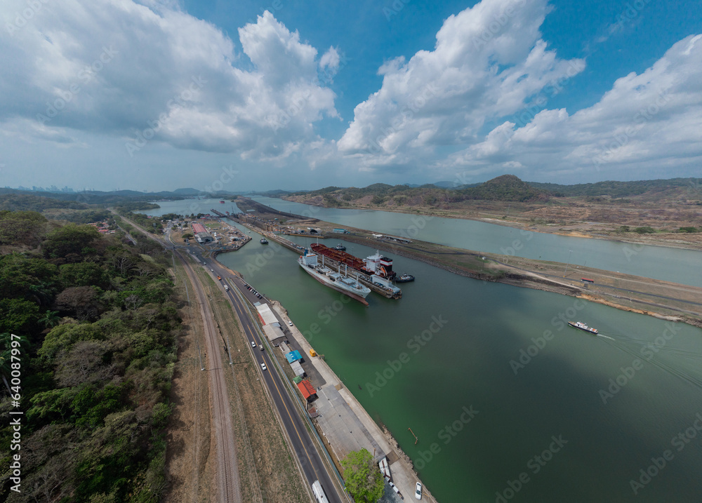 Boat passing Pedro Miguel locks in Panama, famous channel shortcut in central America. Visible ships and channels with locks. Drone view on a cloudy but sunny day in spring.