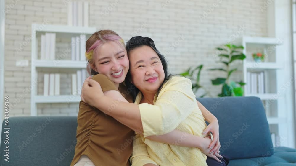 Lovely Asian elderly mom with young daughter hugging cuddle and looking at camera. Young woman and mother spending time together at home. Family moment concept, Mother's day Lovely Asian elderly mom with young daughter hugging cuddle and looking at camera. Young woman and mother spending time together at home. Family moment concept, Mother's day