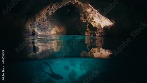 Freediver swims underwater in the cave. Male freediver explores the cave and swimming underwater inside it