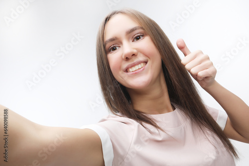 happy smiling young woman wearing taking selfie with smartphone