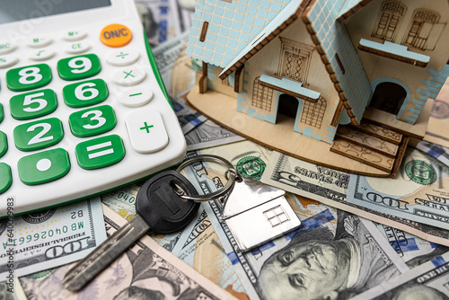 Miniature house with key us money bills and calculator, purchase or rent concept