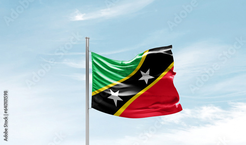 Saint Kitts and Nevis national flag waving in beautiful sky. The symbol of the state on wavy silk fabric.