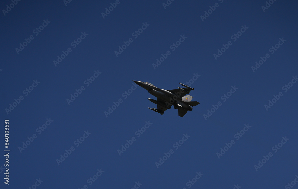 Bucharest International Air Show. F16 military fighter airplane flying against dark blue sky. Military aviation aircrafts and war missiles industry. Bucharest International Air Show. F16 military fighter airplane flying against dark blue sky. Military aviation aircrafts and war missiles industry.
