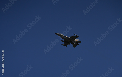 Bucharest International Air Show. F16 military fighter airplane flying against dark blue sky. Military aviation aircrafts and war missiles industry.