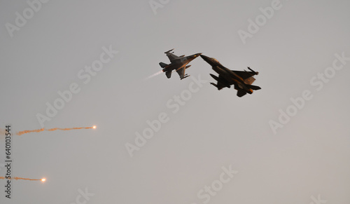 Bucharest International Air Show. F16 military fighter airplane flying against sunset sky. Military aviation aircrafts and war missiles industry.