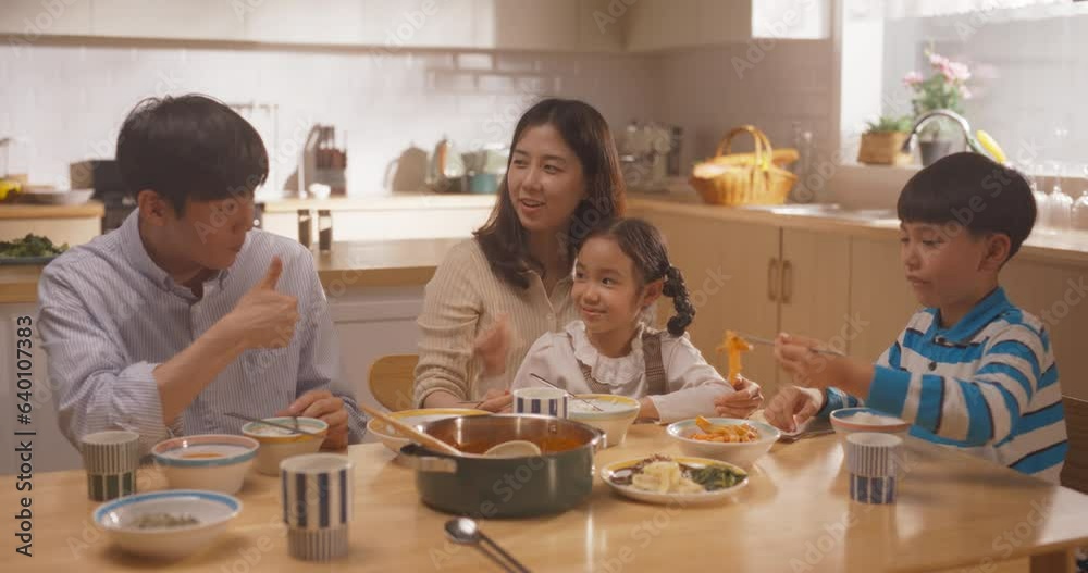 Happy Korean Family of Four Enjoying a Delicious Meal Together in Their Kitchen at Home. Parents and Their Cute Children Gathered For Lunch, Eating and Talking While Sitting at the Table Happy Korean Family of Four Enjoying a Delicious Meal Together in Their Kitchen at Home. Parents and Their Cute Children Gathered For Lunch, Eating and Talking While Sitting at the Table