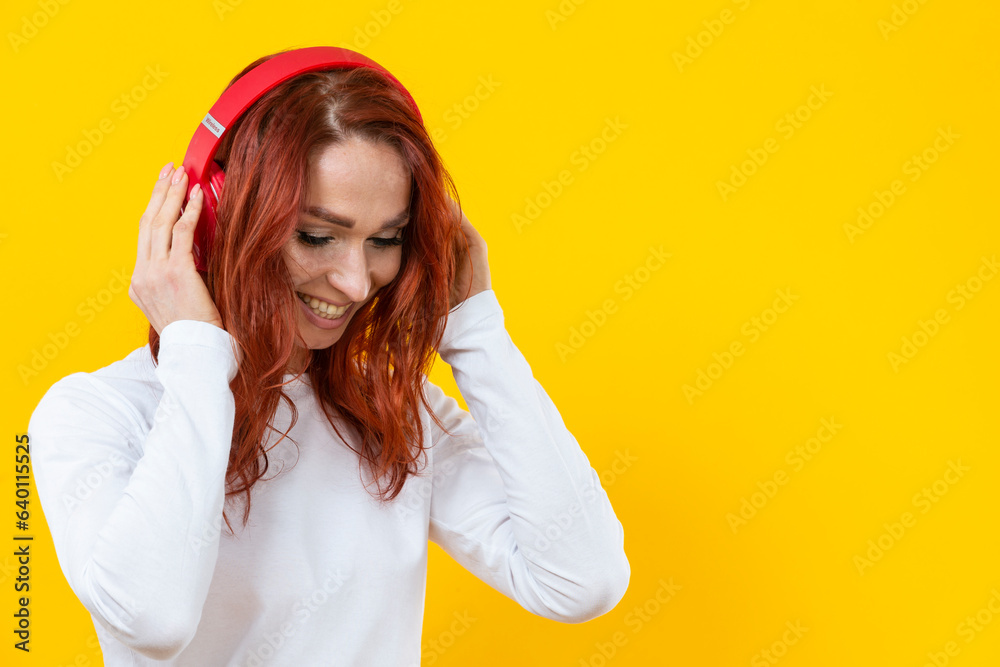 Smiling happy friendly woman in white casual shirt t-shirt wearing red wireless headphones isolated on yellow background studio portrait. Smiling happy friendly woman in white casual shirt t-shirt wearing red wireless headphones isolated on yellow background studio portrait.