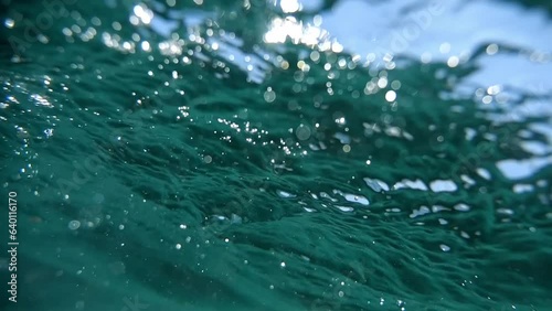 Dive and resurface captured in slow-motion, amidst sunlit, mildly choppy sea waters.