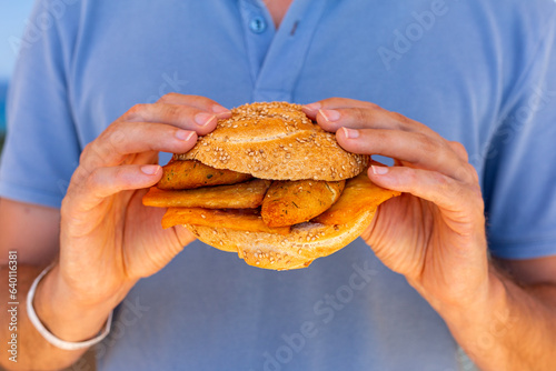 Man hands holding Pane e panelle - chickpea flour fritters in mafalda bread roll, sandwiche, a typical street food of Palermo, Sicily, Italy. Easy and delicious vegan food.