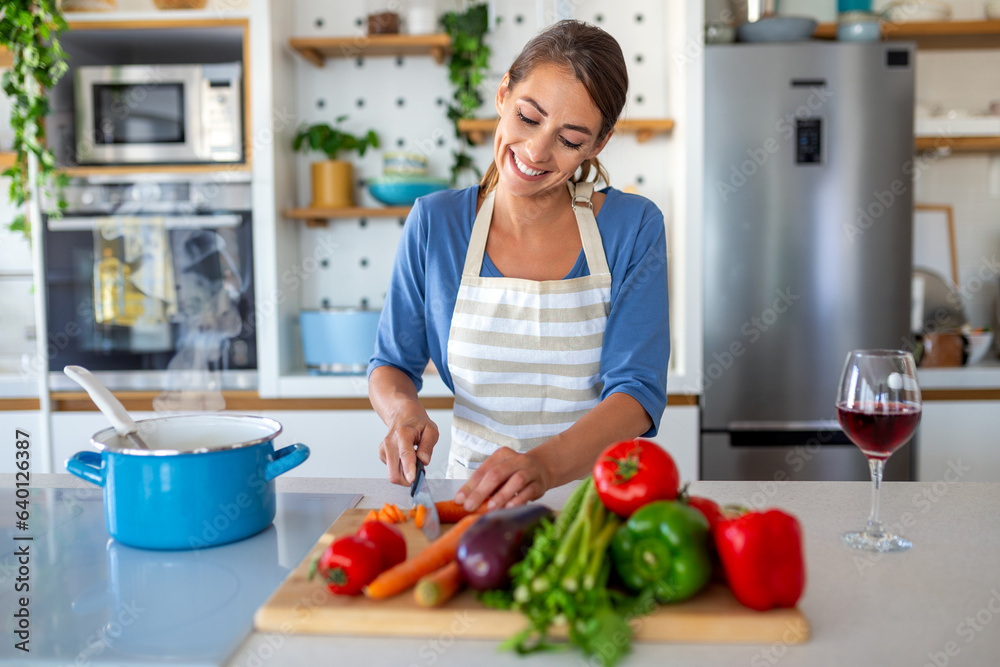 Beautiful young woman stand at modern kitchen chop vegetables prepare fresh vegetable salad for dinner or lunch, young woman cooking at home make breakfast follow healthy diet, vegetarian concept