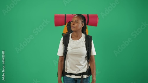 Woman tourist with backpack recording video on her smartphone with happy face expression. Isolated on green background. photo