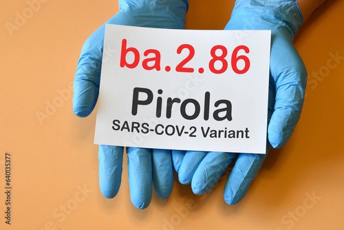 The hands of doctor in blue gloves with white paper and text "ba.2.86 Pirola Variant". Concept for the new variant of SARS-CoV-2 ba.2.86 Pirola Covid-19 New Variants.