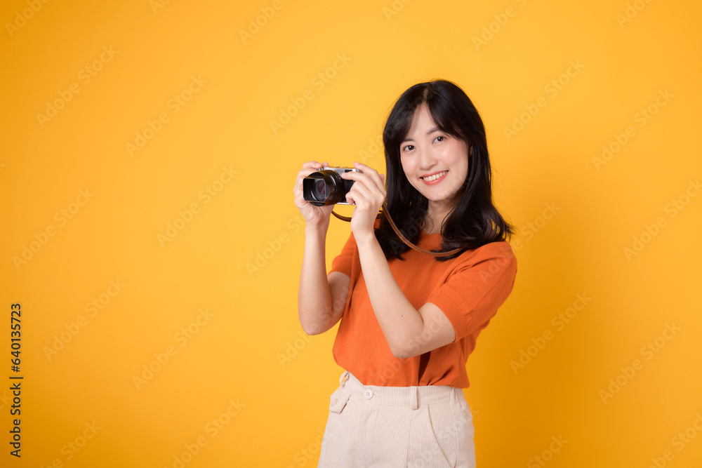 Stylish asian lady traveler with a camera isolated on yellow background, excited for an adventure-filled vacation. Stylish asian lady traveler with a camera isolated on yellow background, excited for an adventure-filled vacation.