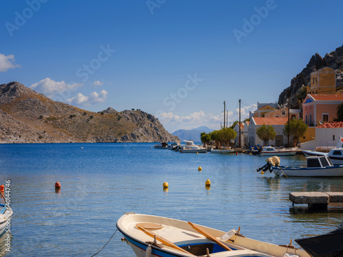 View on Symi or Simi island harbor port, classical ship yachts, houses on island hills, Aegean Sea bay. Greece islands holidays vacation travel tours from Rhodos island. Symi, Greece, Dodecanese.