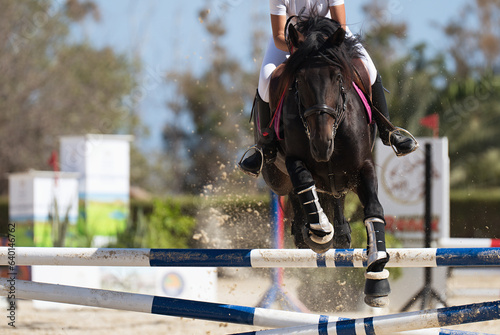 Jockey on her horse leaping over a hurdle, jumping over hurdle on competition 