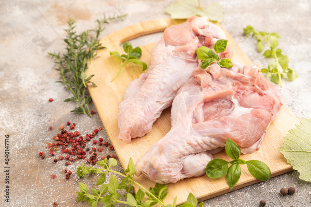 Raw turkey wing on a wooden cutting board on a brown concrete background. Side view, selective focus