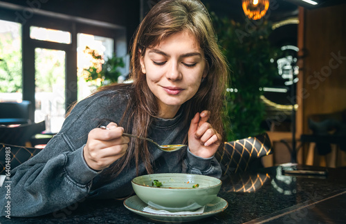 Attractive woman is eating vegetable soup in a cafe. photo