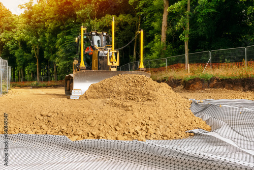 Roadworks and bulldozer levelling stone on top of geogrid plastic mesh photo