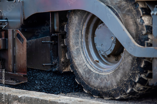 Asphalt paver filled with hot tarmac laying new road surface on new residential housing development site photo