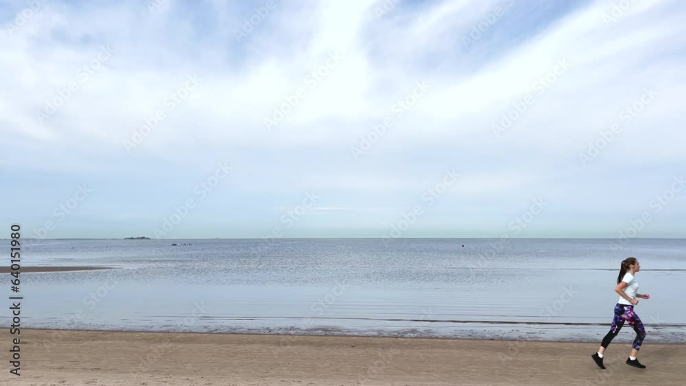 A young girl runs along the sandy seashore. Jogging. Charging. An active lifestyle. Sportswear. Healthy lifestyle. A person does sports.
A young girl runs along the sandy seashore. Jogging. Charging. An active lifestyle. Sportswear. Healthy lifestyle. A person does sports.