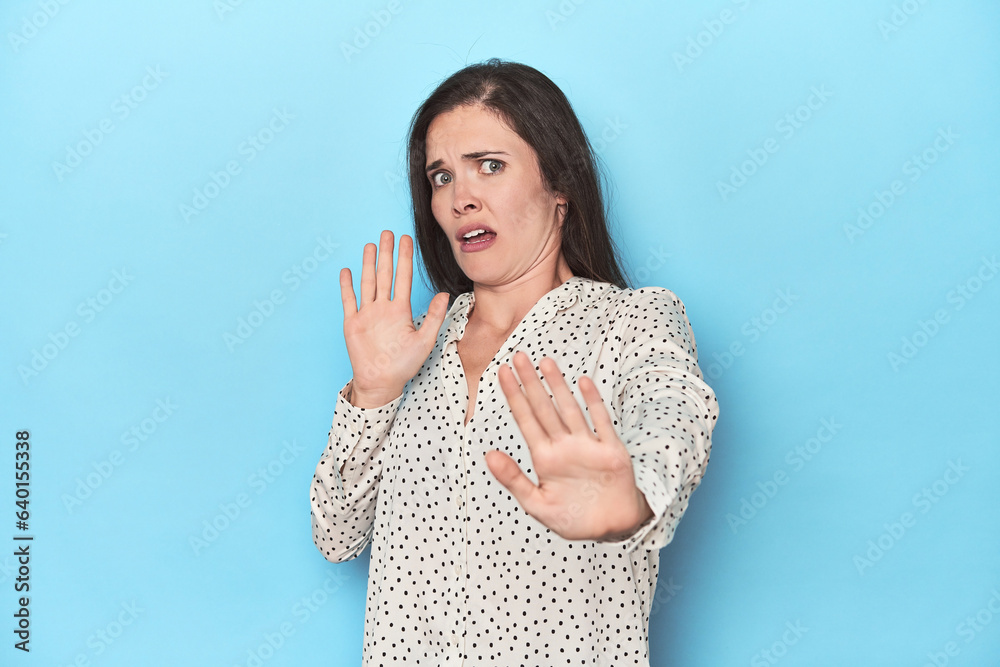 Young caucasian woman on blue backdrop being shocked due to an imminent danger Young caucasian woman on blue backdrop being shocked due to an imminent danger