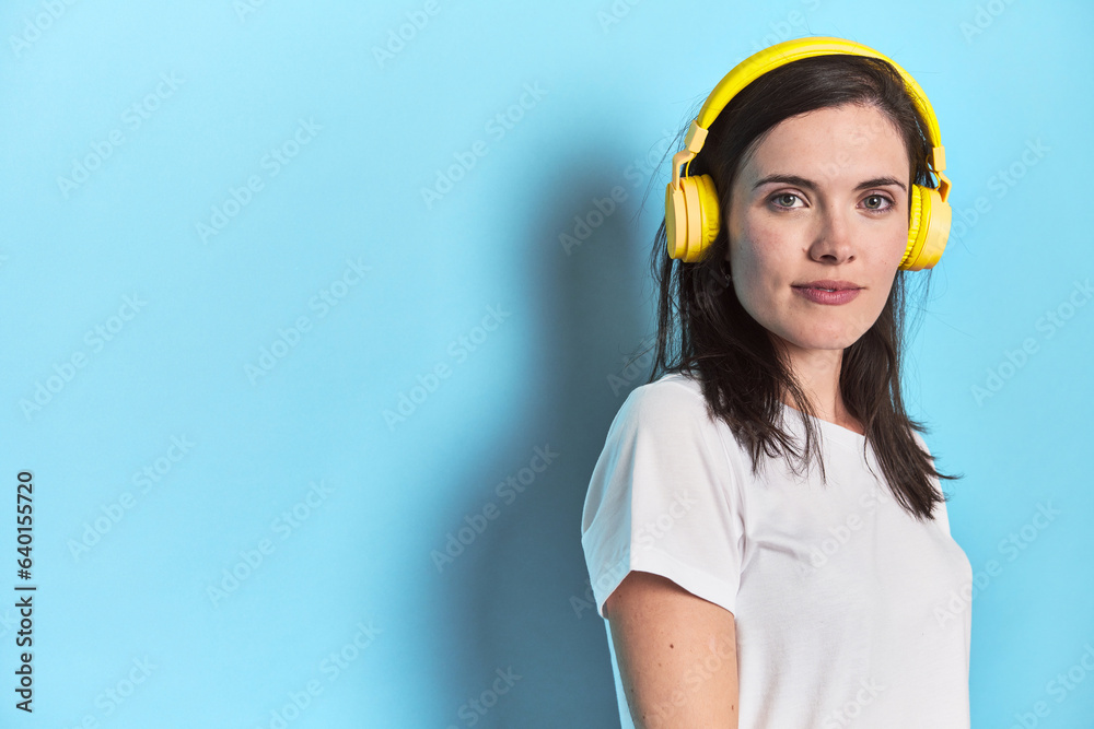 Young woman immersed in music with headphones on blue Young woman immersed in music with headphones on blue