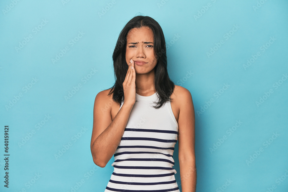 Filipina young woman on blue studio having a strong teeth pain, molar ache. Filipina young woman on blue studio having a strong teeth pain, molar ache.
