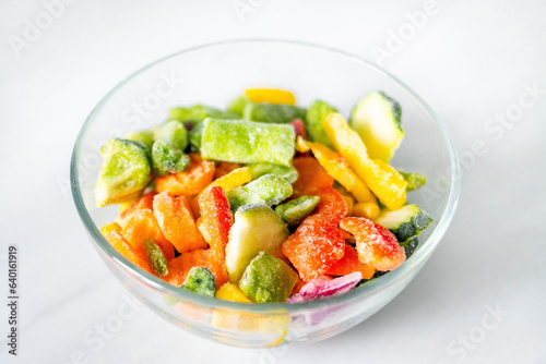 Frozen vegetables in a glass plate on a white background. The concept of healthy eating