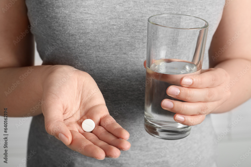 Woman holding glass of water and pill, closeup Woman holding glass of water and pill, closeup
