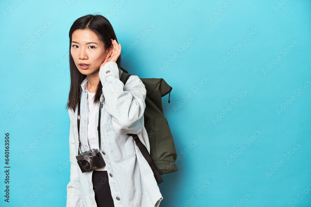 Young Asian traveler ready to capture adventures, trying to listening a gossip.