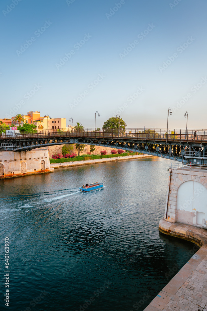 Revolving bridge of the city of Taranto with person crossing it and small boat