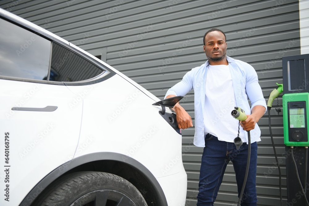 Man Plugging In Electric Car Outside Office In Car Park Charging Man Plugging In Electric Car Outside Office In Car Park Charging