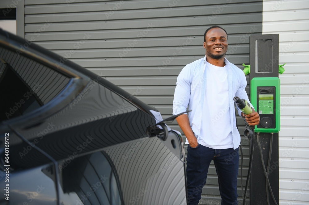 Man Plugging In Electric Car Outside Office In Car Park Charging