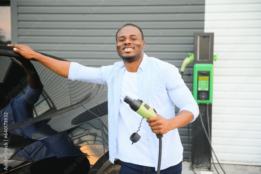 Man Plugging In Electric Car Outside Office In Car Park Charging Man Plugging In Electric Car Outside Office In Car Park Charging