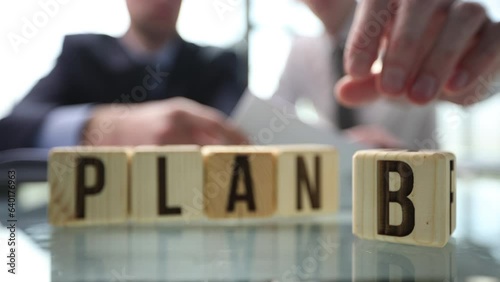 Businessman hand flipping wooden cube blocks with PLAN A change to PLAN B photo