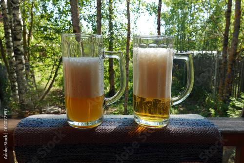 Two big high glasses with fresh beer on the nature  background front view close up photo