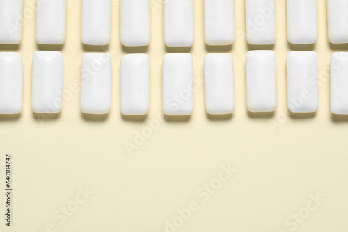 Tasty white chewing gums on beige background  flat lay. Space for text