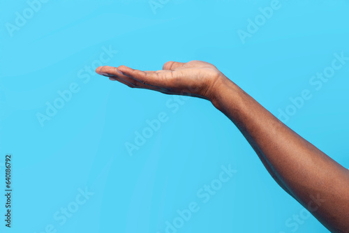 african american man's hand shows copy space on blue isolated background, hand shows empty palm and asks photo