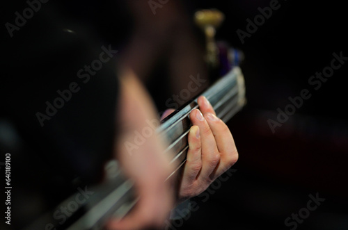 Musician hands playing electric bass guitar  striking a chord  close up