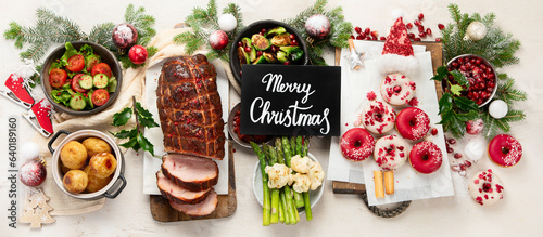 Delicious Christmas themed dinner table with roasted meat, appetizers and desserts. Holiday concept.