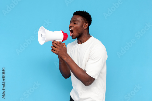 фотографія african american man in white t-shirt announces information into loudspeaker on