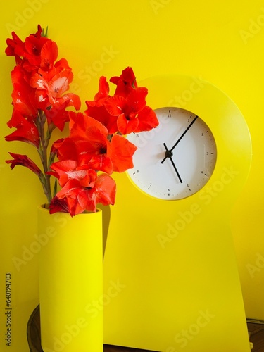 Horloge jaune et fleurs rouges photo