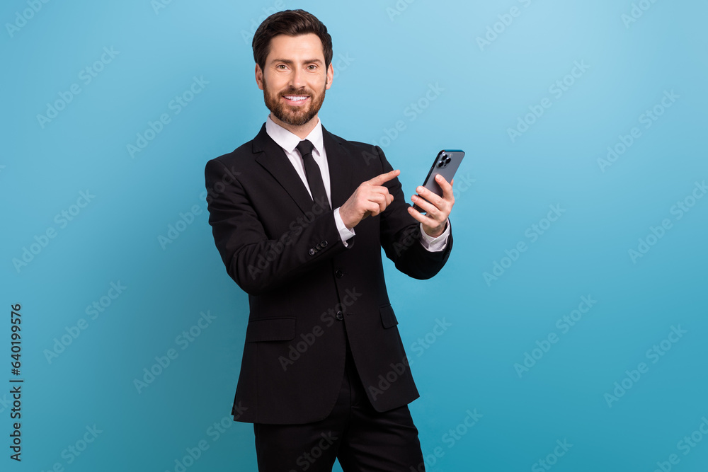 Photo of cheerful happy recruiter dressed black suit pointing finger apple samsung iphone modern device isolated blue color background Photo of cheerful happy recruiter dressed black suit pointing finger apple samsung iphone modern device isolated blue color background